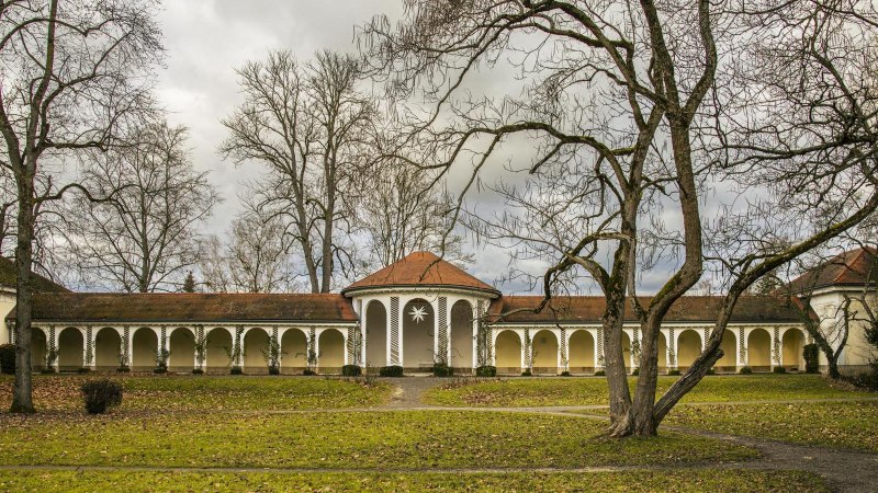 Historisches Kurhaus in Bad Boll mit Arkaden, umgeben von kahlen Bäumen und einem grünen Rasen im Vordergrund., © Stuttgart-Marketing GmbH, Sarah Schmid