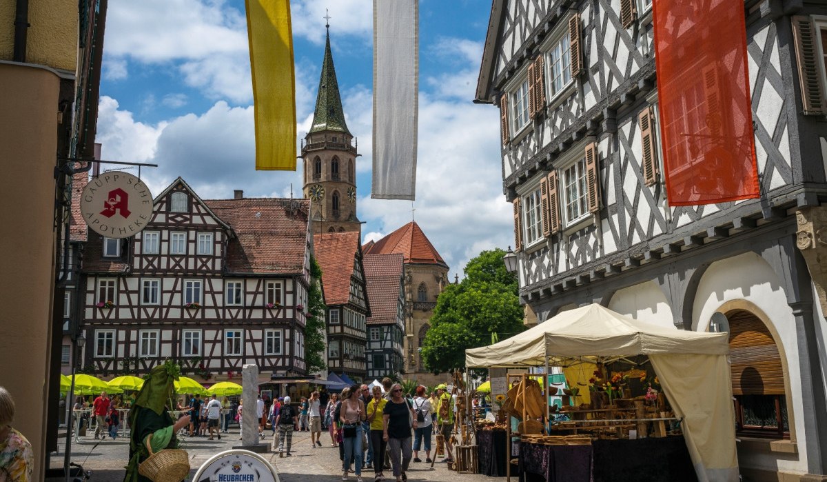Historischer Marktplatz in Schorndorf mit Fachwerkhäusern, Kirchturm im Hintergrund und Marktständen. Menschen flanieren bei sonnigem Wetter., © Remstal Tourismus e.V. Historischer Marktplatz in Schorndorf mit Fachwerkhäusern, Kirchturm im Hintergrund und Marktständen. Menschen flanieren bei sonnigem Wetter., © Remstal Tourismus e.V.