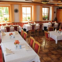 Gemütlicher Gastraum mit gedeckten Tischen, roten Stühlen und orangenen Vorhängen. Pflanzen und Dekorationen verleihen eine einladende Atmosphäre., © Gasthof zur Rose Gemütlicher Gastraum mit gedeckten Tischen, roten Stühlen und orangenen Vorhängen. Pflanzen und Dekorationen verleihen eine einladende Atmosphäre., © Gasthof zur Rose