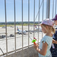 Kinder stehen auf der Besucherterrasse des Stuttgarter Flughafens und schauen durch ein Gitter auf das Rollfeld mit Flugzeugen., © Flughafen Stuttgart Kinder stehen auf der Besucherterrasse des Stuttgarter Flughafens und schauen durch ein Gitter auf das Rollfeld mit Flugzeugen., © Flughafen Stuttgart
