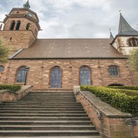 Die St. Peter und Paul Kirche in Weil der Stadt, aufgenommen im Weitwinkel. Eine Treppe führt zur Kirche, umgeben von Bäumen und Sträuchern., © SMG, Sarah Schmid
