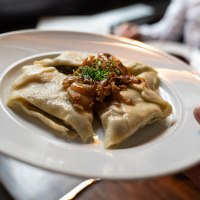 Ein Teller mit Maultaschen, garniert mit Röstzwiebeln und Schnittlauch, wird in einem Restaurant serviert., © Stuttgart-Marketing GmbH, Martina Denker