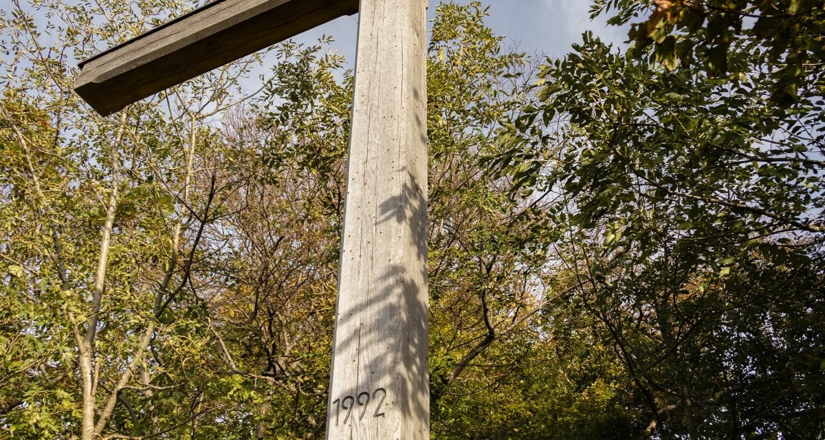 Großes Holzkreuz mit der Jahreszahl 1992 vor Bäumen und blauem Himmel., © Foto Thomas Zehnder Großes Holzkreuz mit der Jahreszahl 1992 vor Bäumen und blauem Himmel., © Foto Thomas Zehnder