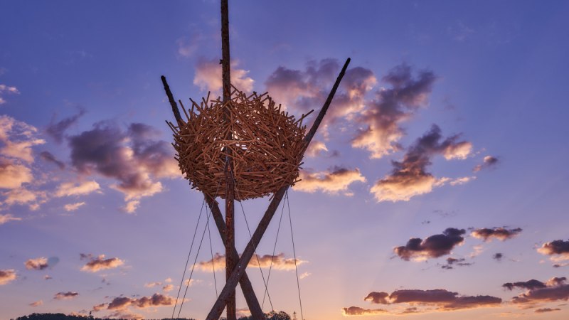 Eine gro&szlig;e Vogelnest-Skulptur aus Holz thront vor einem dramatischen Sonnenuntergang mit violettem Himmel und Wolken., &copy; Natur.Nah. Sch&ouml;nbuch & Heckeng&auml;u