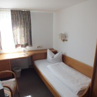 Ein kleines Einzelzimmer mit einem Bett, einem Schreibtisch, einem Stuhl und einem Fenster mit Vorhängen., © Gasthof zum Bären