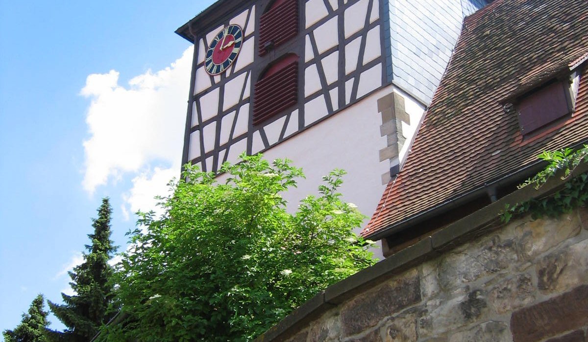 Fachwerkkirchturm der St. Veit Kirche in Ensingen mit Uhr und rotem Dach vor blauem Himmel., © Land der 1000 Hügel - Kraichgau-Stromberg Fachwerkkirchturm der St. Veit Kirche in Ensingen mit Uhr und rotem Dach vor blauem Himmel., © Land der 1000 Hügel - Kraichgau-Stromberg