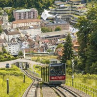 Die Sommerbergbahn fährt durch grüne Landschaft auf Bad Wildbad zu. Im Hintergrund sind Gebäude und Bäume zu sehen., © Stuttgart-Marketing GmbH, Sarah Schmid Die Sommerbergbahn fährt durch grüne Landschaft auf Bad Wildbad zu. Im Hintergrund sind Gebäude und Bäume zu sehen., © Stuttgart-Marketing GmbH, Sarah Schmid