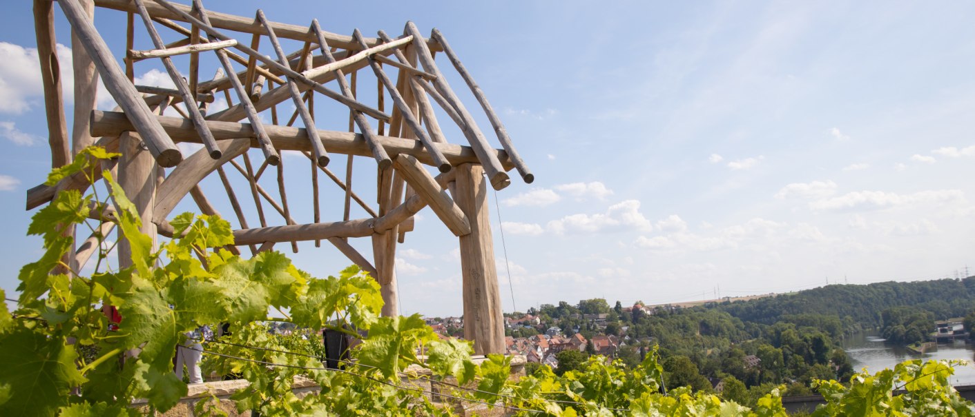 Holzger&uuml;st mit Weinreben im Vordergrund, dahinter eine Stadt und ein Fluss unter blauem Himmel., &copy; SMG, Antje Seeling