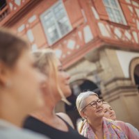 Eine Gruppe von Menschen steht vor einem historischen Fachwerkhaus in Waiblingen. Die Personen blicken interessiert in eine Richtung., © WTM GmbH Waiblingen