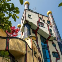 Das Hundertwasserhaus in Plochingen zeigt seine charakteristische bunte Fassade und organische Formen, umgeben von gr&uuml;nen Bl&auml;ttern und blauem Himmel., &copy; Stuttgart-Marketing GmbH, Sarah Schmid