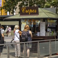 Ein Crêpes-Stand am Stuttgarter Hauptbahnhof mit mehreren Menschen, die anstehen. Im Hintergrund sind Fahrräder und ein Bus zu sehen., © SMG, Sarah Schmid Ein Crêpes-Stand am Stuttgarter Hauptbahnhof mit mehreren Menschen, die anstehen. Im Hintergrund sind Fahrräder und ein Bus zu sehen., © SMG, Sarah Schmid
