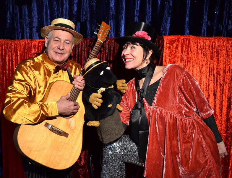 Zwei Personen in bunten Kostümen posieren mit einer Maulwurf-Puppe und Gitarre vor einem roten Vorhang., © FILharmonie Filderstadt Zwei Personen in bunten Kostümen posieren mit einer Maulwurf-Puppe und Gitarre vor einem roten Vorhang., © FILharmonie Filderstadt