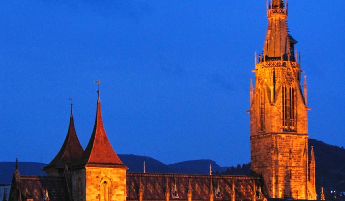 Eine beleuchtete Kirche in Reutlingen bei Nacht, umgeben von Häuserdächern. Der Himmel ist dunkelblau., © Mythos Schwäbische Alb im Landkreis Reutlingen e.V. Eine beleuchtete Kirche in Reutlingen bei Nacht, umgeben von Häuserdächern. Der Himmel ist dunkelblau., © Mythos Schwäbische Alb im Landkreis Reutlingen e.V.