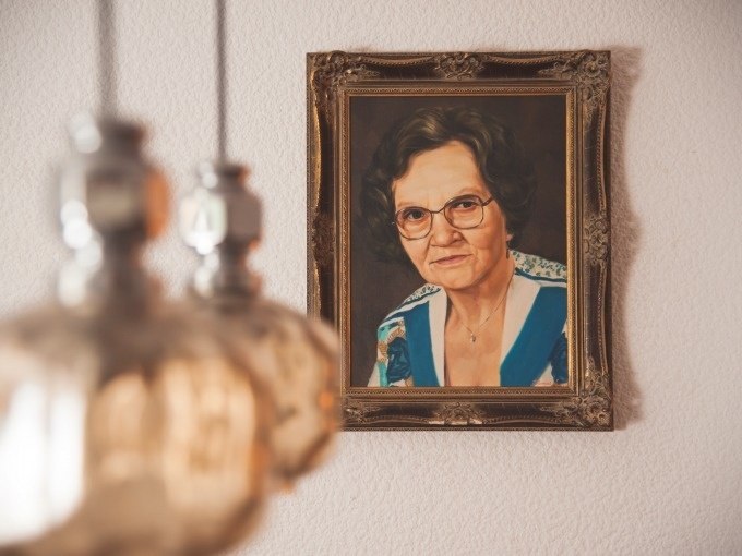 Ein Gem&auml;lde einer &auml;lteren Frau in einem verzierten Rahmen h&auml;ngt an einer Wand. Im Vordergrund sind unscharfe Lampen zu sehen., &copy; ExitGames Stuttgart