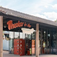 Eingang des Theaters in der Badewanne mit Glasfront und rotem Auto davor. Ein Schild mit dem Theaternamen und einer Badewanne ist sichtbar., © Stuttgart Marketing GmbH, Sarah Schmid