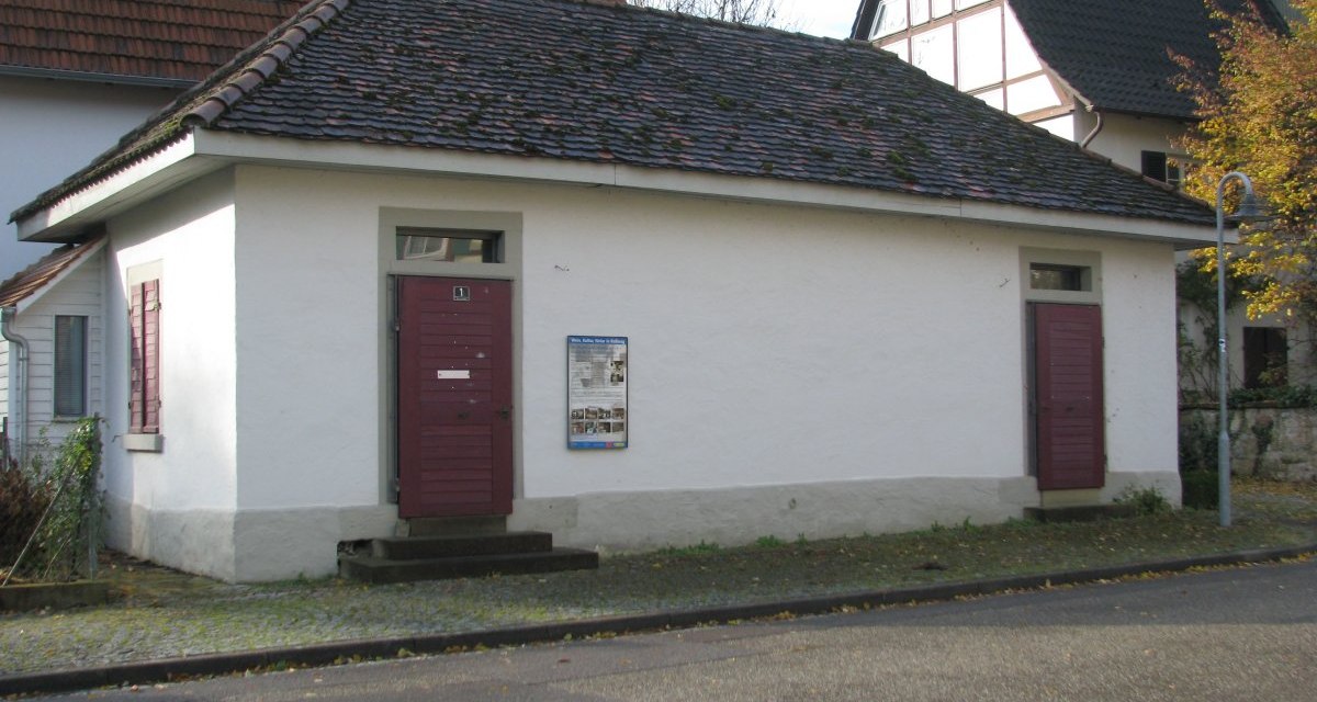 Kleines, wei&szlig;es Geb&auml;ude mit roten T&uuml;ren und Ziegeldach, umgeben von Wohnh&auml;usern. Ein Schild ist an der Wand angebracht., &copy; Land der 1000 H&uuml;gel - Kraichgau-Stromberg