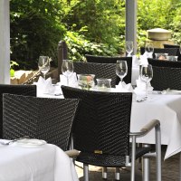 Elegante Restaurantterrasse mit gedeckten Tischen, wei&szlig;en Tischdecken und Weingl&auml;sern, umgeben von gr&uuml;ner Vegetation., &copy; cSchupfnudl