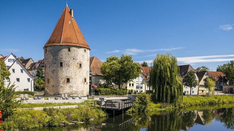 Runder Turm mit rotem Dach am Fluss, umgeben von Häusern und Bäumen, blauer Himmel., © Stuttgart-Marketing GmbH, Sarah Schmid