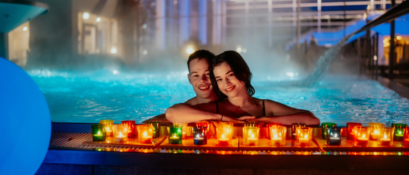 Ein Paar entspannt im Pool, umgeben von leuchtenden Kerzen, die eine romantische Atmosph&auml;re schaffen., &copy; Nik Ebert