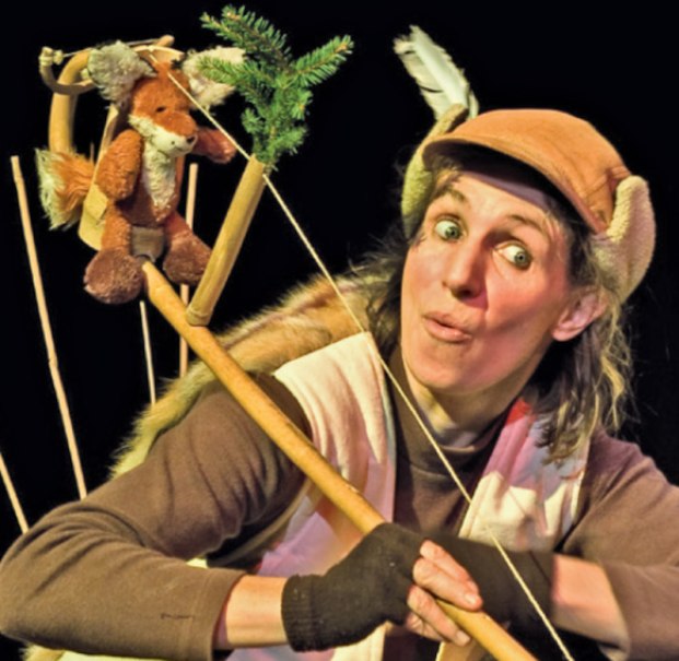 Frau mit Mütze und Handschuhen hält einen Stock mit Plüschfuchs und Zweigen, schaut überrascht., © Theaterwerkstatt Schwäbisch Gmünd e.V.