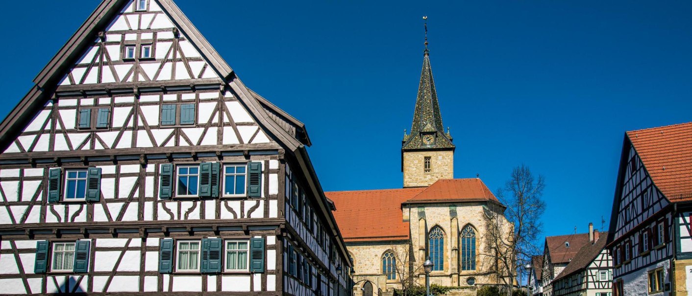 Fachwerkh&auml;user und eine Kirche in Kornwestheim vor blauem Himmel. Die Architektur zeigt traditionelle Bauweise mit markanten Holzbalken., &copy; Stuttgart-Marketing GmbH, Sarah Schmid