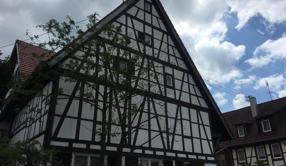 Altes Fachwerkhaus mit dunklen Holzbalken und weißen Wänden, umgeben von Bäumen, unter einem bewölkten Himmel., © Natur.Nah. Schönbuch & Heckengäu Altes Fachwerkhaus mit dunklen Holzbalken und weißen Wänden, umgeben von Bäumen, unter einem bewölkten Himmel., © Natur.Nah. Schönbuch & Heckengäu