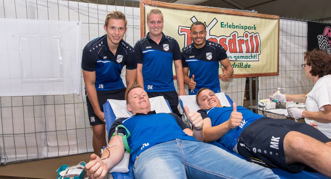 Zwei M&auml;nner spenden Blut, w&auml;hrend drei weitere in Sportkleidung daneben stehen und l&auml;cheln. Eine Frau betreut die Blutspende., &copy; Erlebnispark Tripsdrill