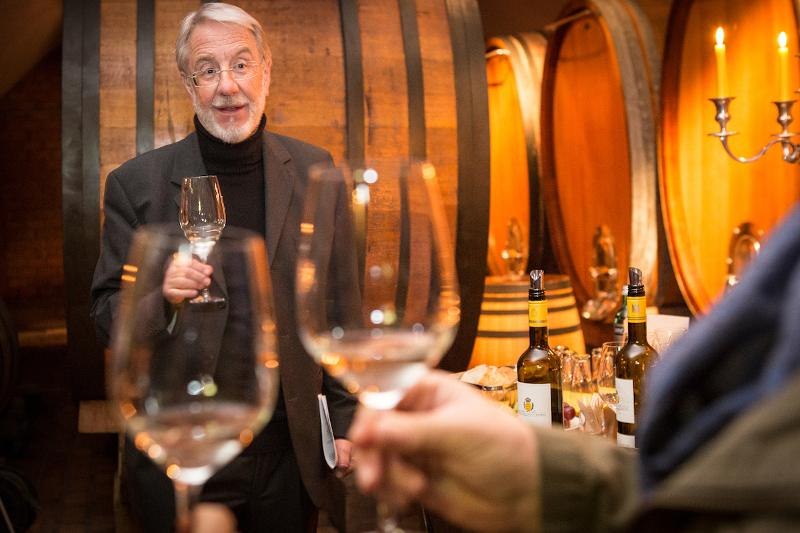 Ein Mann in einem Weinkeller h&auml;lt ein Weinglas. Im Hintergrund sind gro&szlig;e Holzf&auml;sser und Kerzenleuchter zu sehen., &copy; &copy; T&E, Benjamin Stollenberg