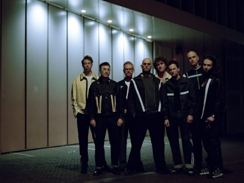 Acht Personen posieren vor einem beleuchteten Gebäude. Sie tragen dunkle Kleidung und stehen in einer Reihe., © Jazzclub Schwäbisch Hall e.V.