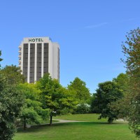 Hotelgeb&auml;ude hinter B&auml;umen in einem Park, blauer Himmel., &copy; AMBER HOTEL Leonberg / Stuttgart