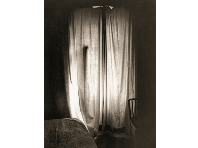 Ein schattiger Raum mit einem Bett und einem Stuhl. Licht f&auml;llt durch einen geschlossenen Vorhang und erzeugt eine ruhige Atmosph&auml;re., &copy; Kunsthalle G&ouml;ppingen