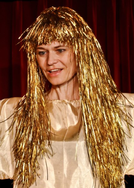 Person mit goldener Perücke und Kostüm steht vor einem roten Vorhang, vermutlich in einem Theaterstück., © Galli Theater Backnang