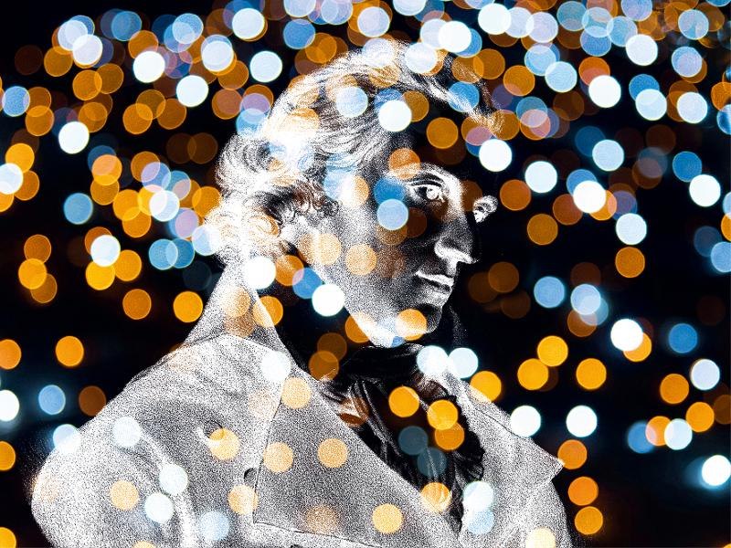 Eine Statue vor einem Hintergrund aus unscharfen, bunten Lichtern, die eine festliche Atmosphäre erzeugen., © Backnang Eine Statue vor einem Hintergrund aus unscharfen, bunten Lichtern, die eine festliche Atmosphäre erzeugen., © Backnang