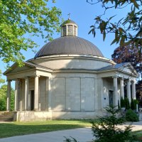 Frasch Mausoleum auf dem Friedhof in Gaildorf: helles Steingebäude mit grauer Kuppel umgeben von Bäumen und Grünflächen. Von Säulen getragene Vordächer schützen zwei Eingangstüren, zu denen Stufen hinaufführen., © Petra Natzkowski Frasch Mausoleum auf dem Friedhof in Gaildorf: helles Steingebäude mit grauer Kuppel umgeben von Bäumen und Grünflächen. Von Säulen getragene Vordächer schützen zwei Eingangstüren, zu denen Stufen hinaufführen., © Petra Natzkowski