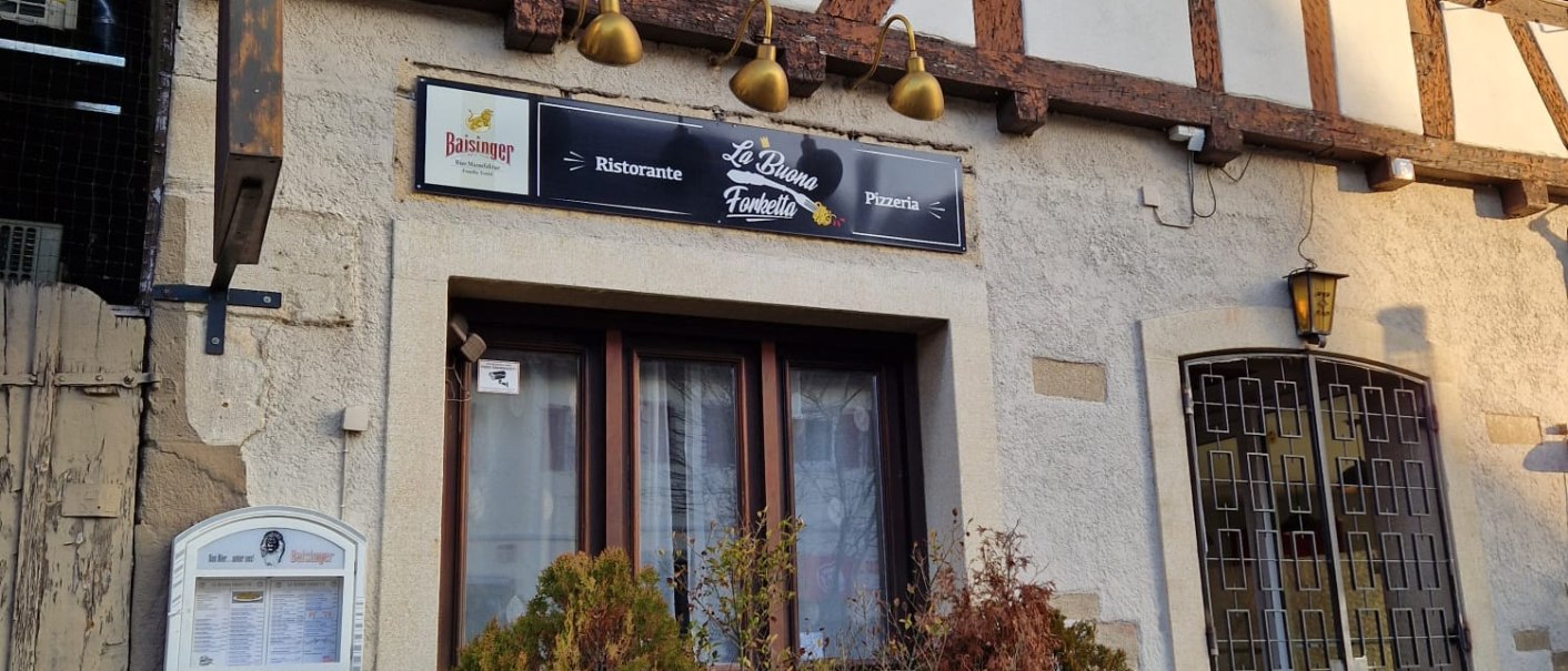 Fachwerkhaus mit dem Restaurant La buona Forketta. Ein Schild bewirbt den Mittagstisch mit Pizza oder Pasta. Pflanzen in Kübeln vor dem Eingang., © cStadtNuertingen Fachwerkhaus mit dem Restaurant La buona Forketta. Ein Schild bewirbt den Mittagstisch mit Pizza oder Pasta. Pflanzen in Kübeln vor dem Eingang., © cStadtNuertingen
