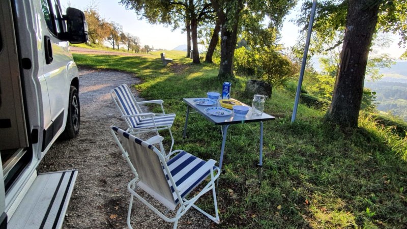 Wohnmobilstellplatz mit Tisch und Stühlen im Grünen. Teller und Gläser auf dem Tisch, umgeben von Bäumen und mit Blick auf die Landschaft., © Stadtmarketing Göppingen Wohnmobilstellplatz mit Tisch und Stühlen im Grünen. Teller und Gläser auf dem Tisch, umgeben von Bäumen und mit Blick auf die Landschaft., © Stadtmarketing Göppingen