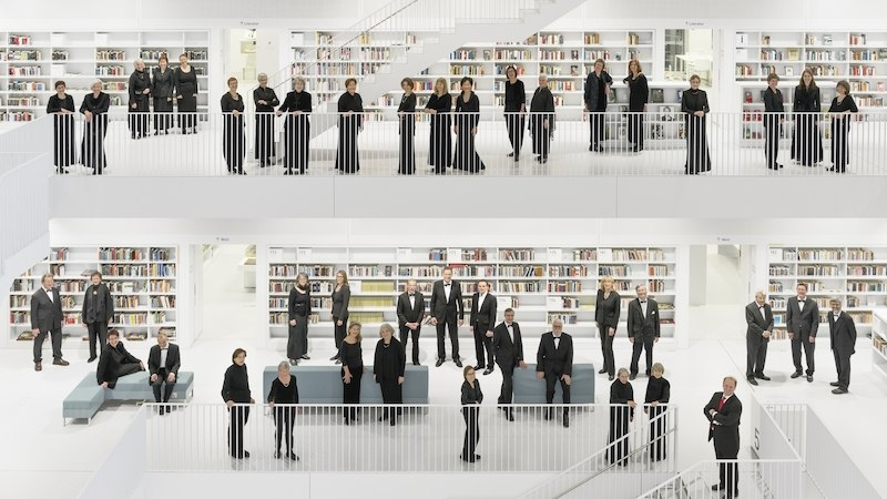 Eine Gruppe von Menschen in schwarzer Kleidung steht in einer modernen, weißen Bibliothek mit mehreren Etagen und Bücherregalen., © Schönblick gemeinnützige GmbH