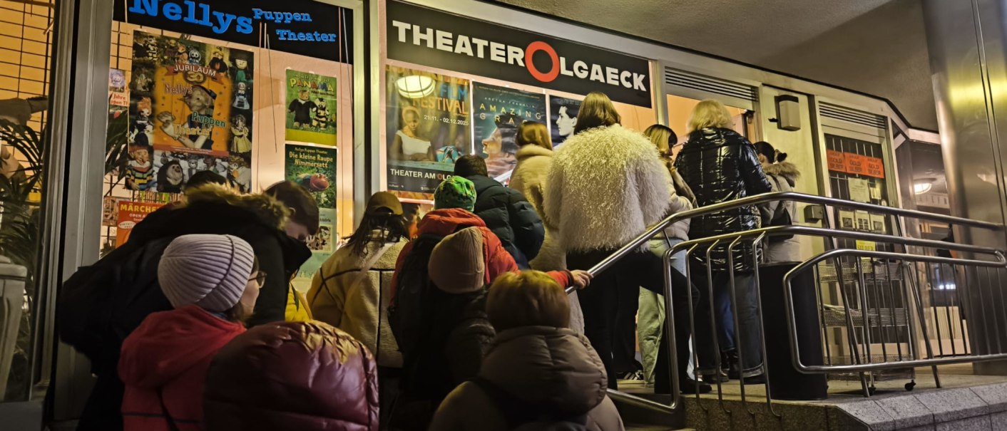 Abendliche Warteschlange vor dem Theater am Olgaeck in Stuttgart mit Plakaten für Puppentheater und Filmfestival., © Theater am Olgaeck Abendliche Warteschlange vor dem Theater am Olgaeck in Stuttgart mit Plakaten für Puppentheater und Filmfestival., © Theater am Olgaeck