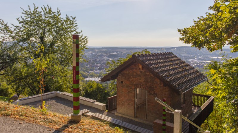 Kleines Backsteinhaus in den Metzinger Weinbergen, umgeben von Bäumen, mit Blick auf die Stadt im Hintergrund., © SMG Mende