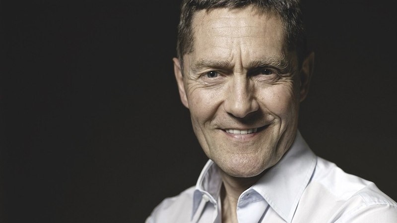 Ein Mann in einem wei&szlig;en Hemd l&auml;chelt in die Kamera. Der Hintergrund ist dunkel, was den Fokus auf das Gesicht lenkt., &copy; Kulturstiftung Hohenlohe