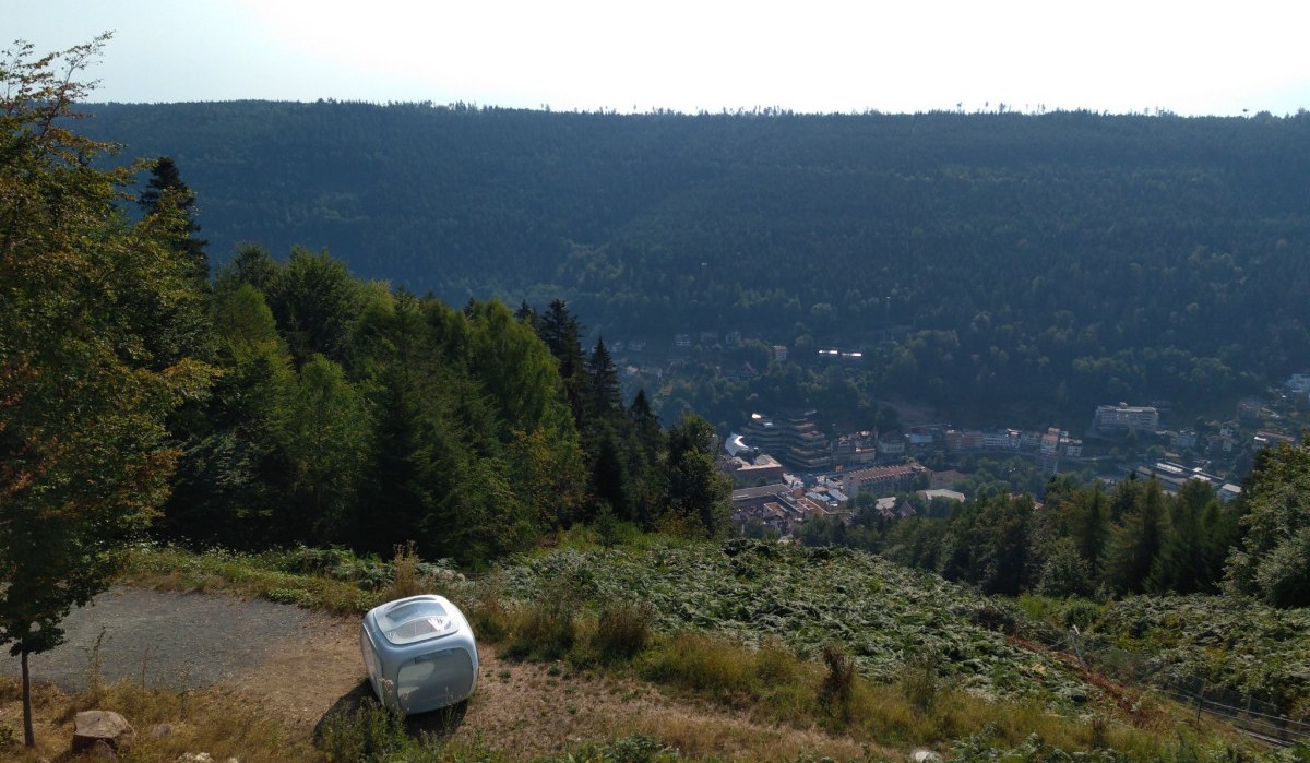 Ein kleiner Wohnwagen steht auf einem H&uuml;gel mit Blick auf ein Tal und eine Stadt, umgeben von dichtem Wald., &copy; N&ouml;rdlicher Schwarzwald