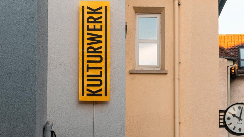 Ein gelbes Schild mit der Aufschrift 'KULTURWERK' h&auml;ngt an einer Hauswand. Daneben ist ein Fenster und eine Uhr zu sehen., &copy; Stuttgart-Marketing GmbH, Sarah Schmid