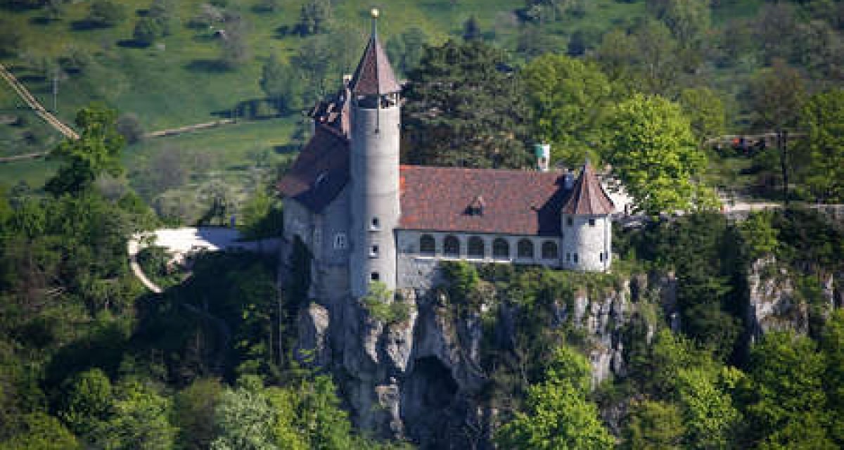 Luftaufnahme der Burg Teck, die auf einem bewaldeten Hügel thront. Die Burg hat einen runden Turm und ein rotes Ziegeldach., © Schwäbische Alb Luftaufnahme der Burg Teck, die auf einem bewaldeten Hügel thront. Die Burg hat einen runden Turm und ein rotes Ziegeldach., © Schwäbische Alb