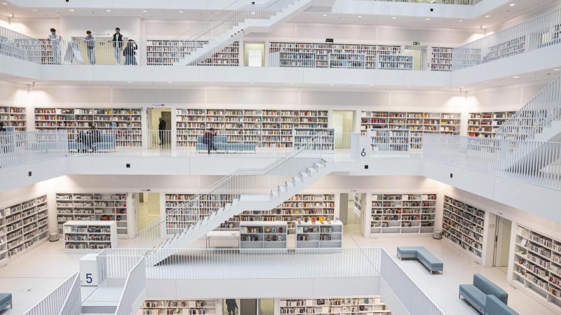 Innenansicht der Stadtbibliothek Stuttgart mit mehreren Etagen, weißen Wänden und Regalen voller Bücher. Menschen bewegen sich auf den Ebenen., © Stuttgart-Marketing GmbH, Sarah Schmid