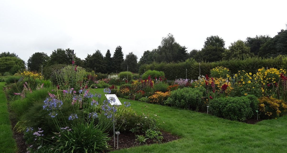 Ein gepflegter Garten mit bunten Blumenbeeten, grünem Rasen und Bäumen im Hintergrund unter bewölktem Himmel., © Nürtingen - Stuttgart-Marketing GmbH Ein gepflegter Garten mit bunten Blumenbeeten, grünem Rasen und Bäumen im Hintergrund unter bewölktem Himmel., © Nürtingen - Stuttgart-Marketing GmbH