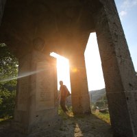 Ein Ehrenmal auf einem Hügel, beleuchtet von der untergehenden Sonne. Eine Person steht im Hintergrund, umgeben von Natur., © Bad Urach Tourismus