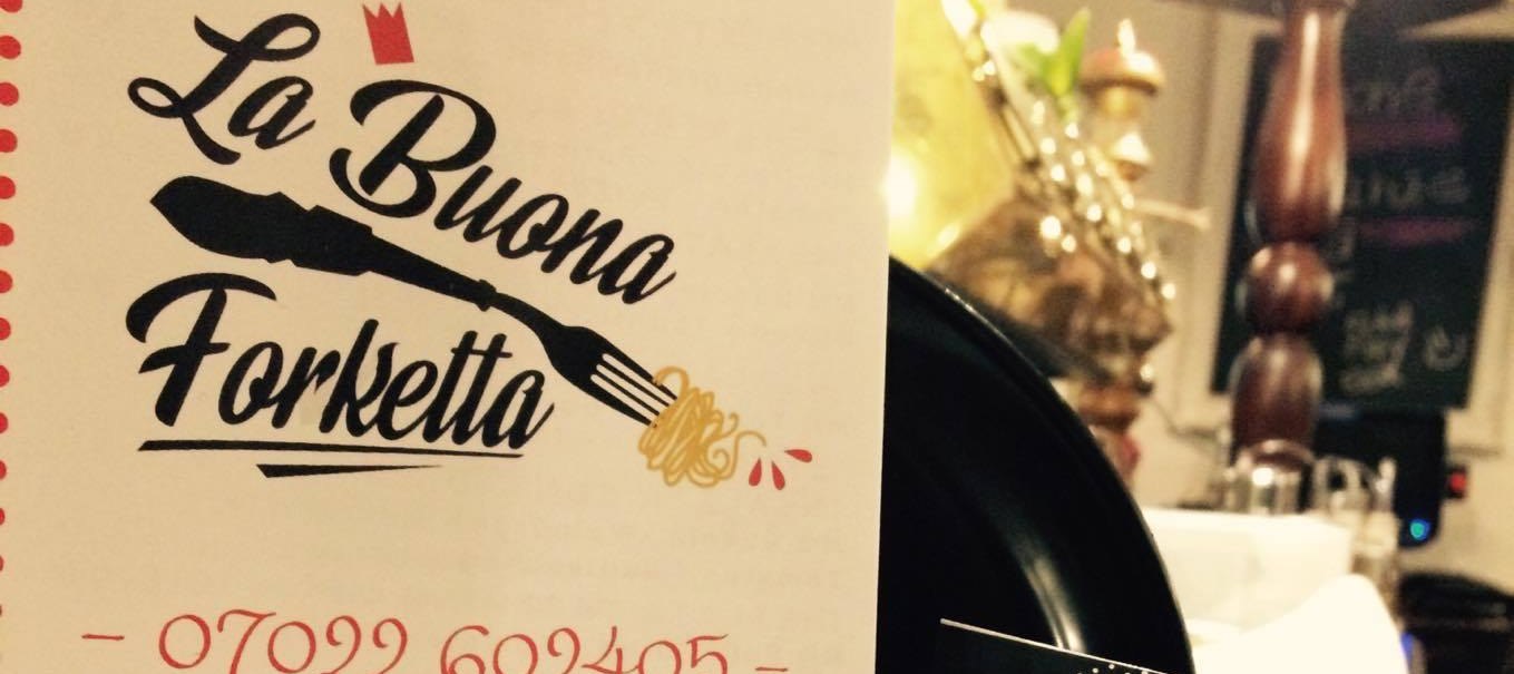 Speisekarte und Visitenkarten des Restaurants La Buona Forketta mit Gabel-Logo und Telefonnummer, dekorativ auf einem Tisch arrangiert., © La buona forketta Speisekarte und Visitenkarten des Restaurants La Buona Forketta mit Gabel-Logo und Telefonnummer, dekorativ auf einem Tisch arrangiert., © La buona forketta