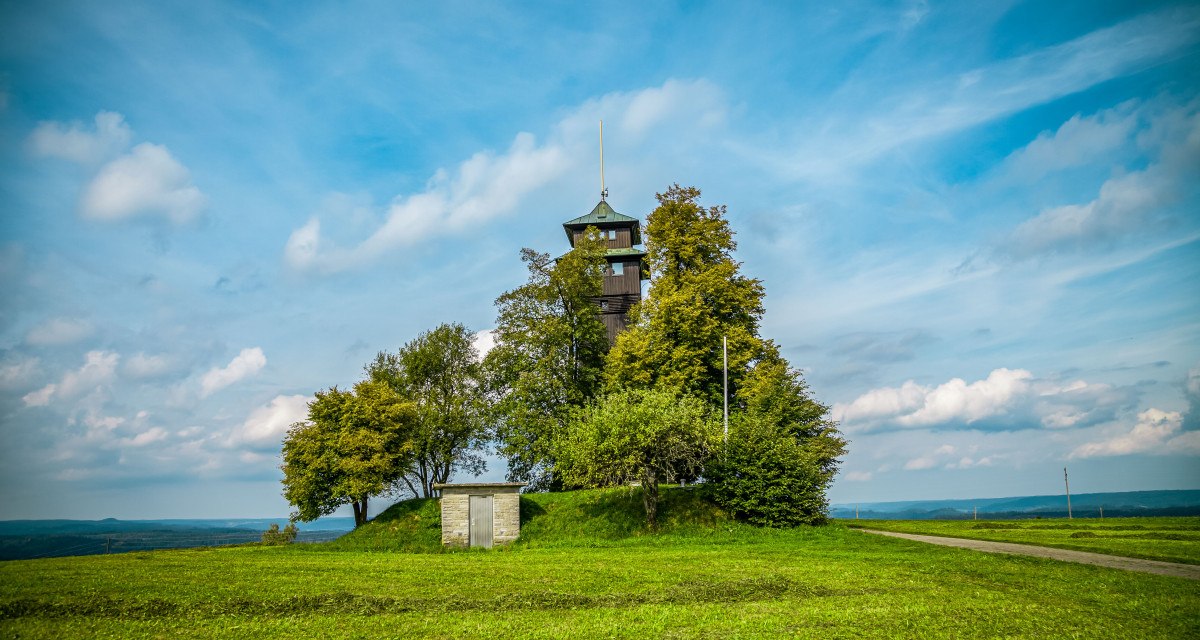Der Hagbergturm in Gschwend steht auf einem Hügel, umgeben von Bäumen und einer grünen Wiese. Ein kleiner Weg führt zum Turm, der Himmel ist blau mit Wolken., © agentur arcos/Niki Eilers Der Hagbergturm in Gschwend steht auf einem Hügel, umgeben von Bäumen und einer grünen Wiese. Ein kleiner Weg führt zum Turm, der Himmel ist blau mit Wolken., © agentur arcos/Niki Eilers