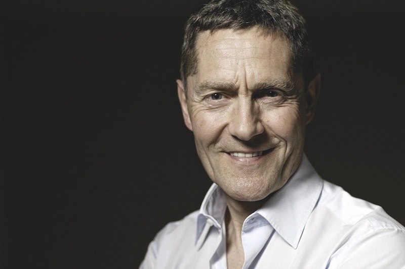 Ein Mann in einem wei&szlig;en Hemd l&auml;chelt in die Kamera. Der Hintergrund ist dunkel, was den Fokus auf das Gesicht lenkt., &copy; Kulturstiftung Hohenlohe