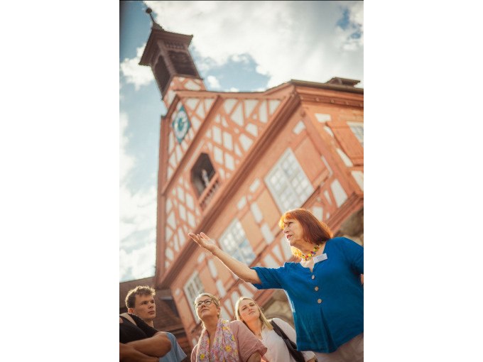 Eine Frau erkl&auml;rt einer Gruppe etwas vor einem historischen Fachwerkgeb&auml;ude in Waiblingen. Der Himmel ist leicht bew&ouml;lkt., &copy; WTM GmbH Waiblingen